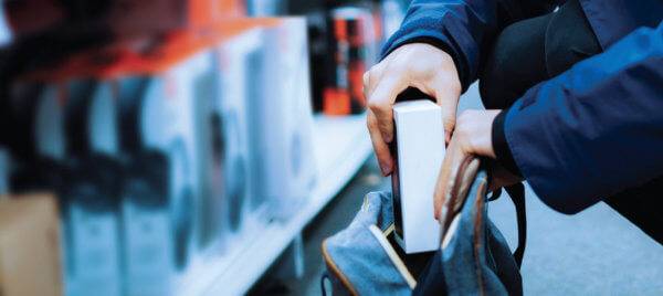 A close up of a person shoplifting an item into their bag