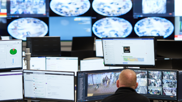 Man examining security footage on a bank of screens