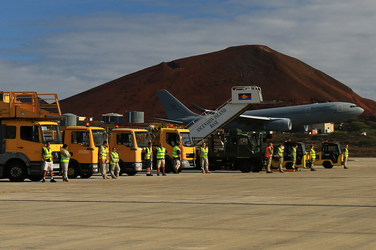 Aircraft parked on a runway with Mitie staff and other supporting vehicles nearby