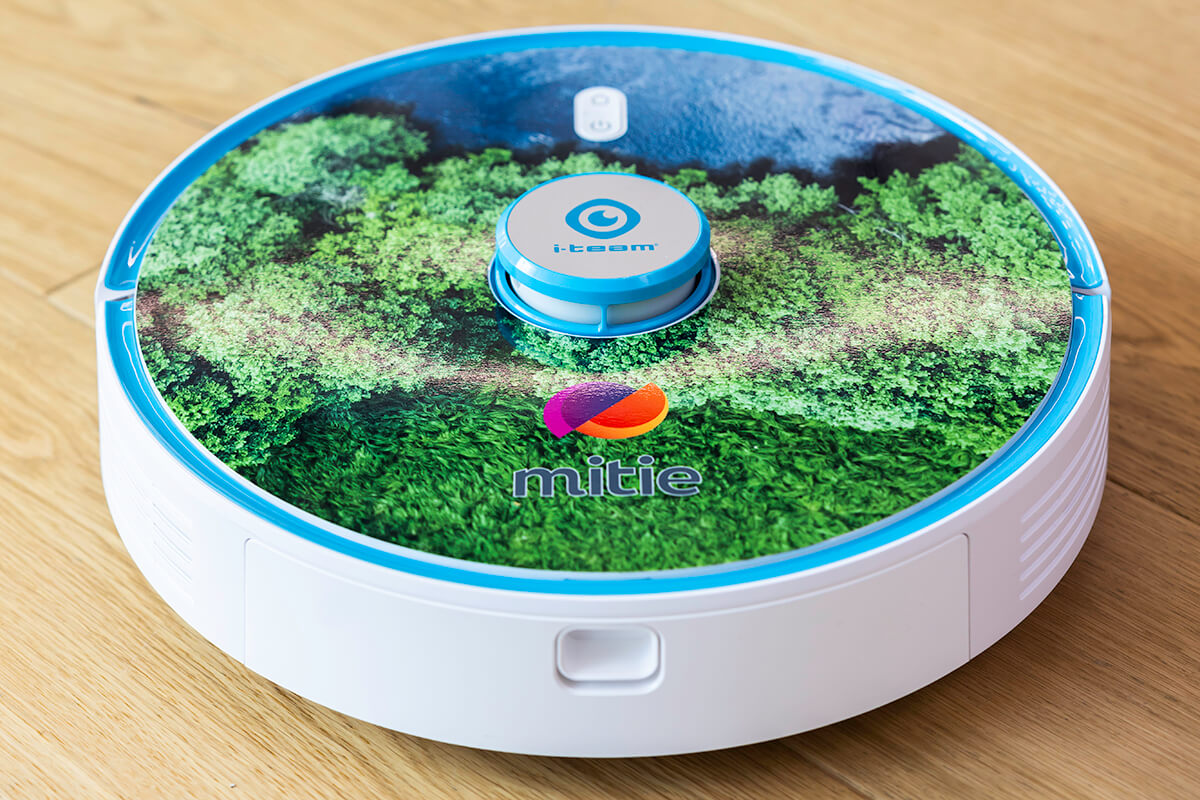 A round robot hoover, with Mitie branding and a print of green trees on the top