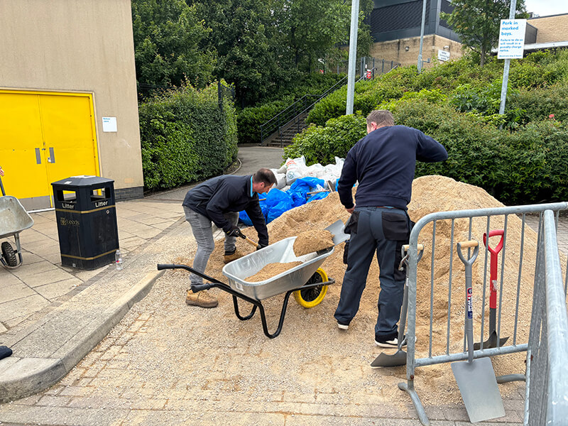 Mitie colleagues filling a wheelbarrow with gravel