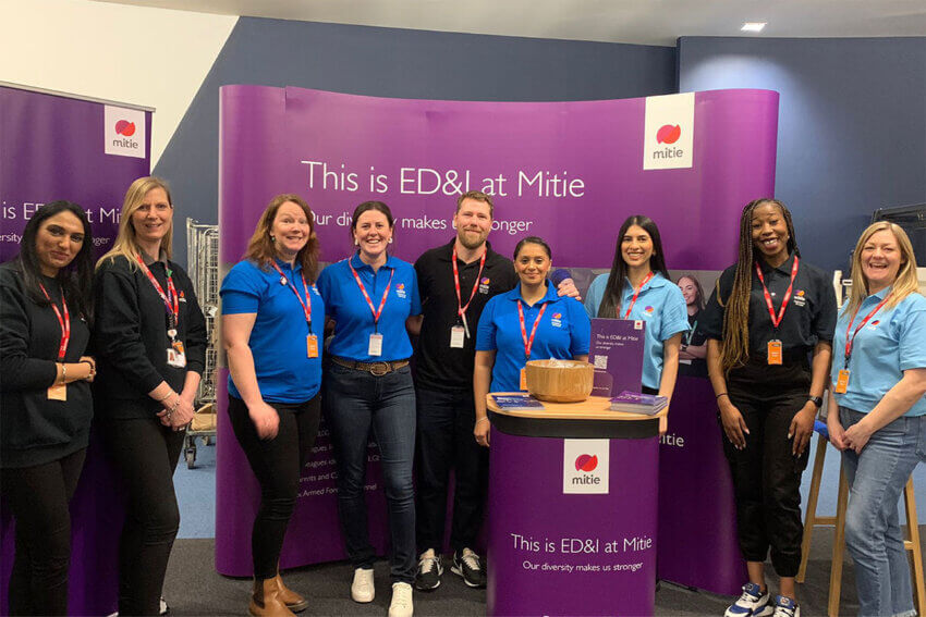 A group of Mitie colleagues in front of banners 'This is ED&I at Mitie'