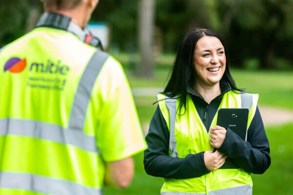 Two Mitie colleagues smiling and wearing high vis vests