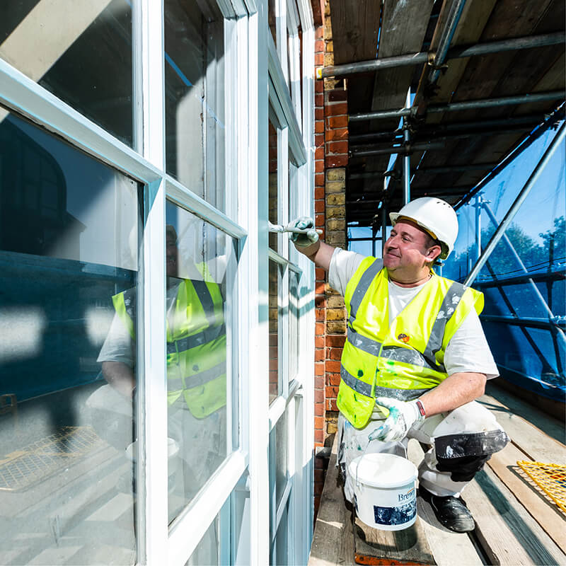 Mitie colleague painting a window frame